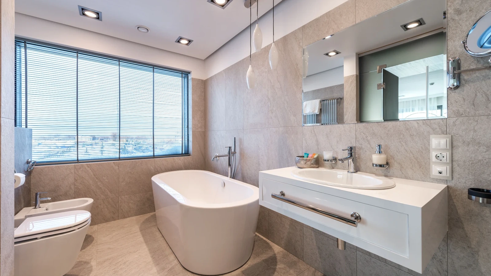 Bright bathroom with stone-look wall tiles, a freestanding white bathtub and floating vanity.