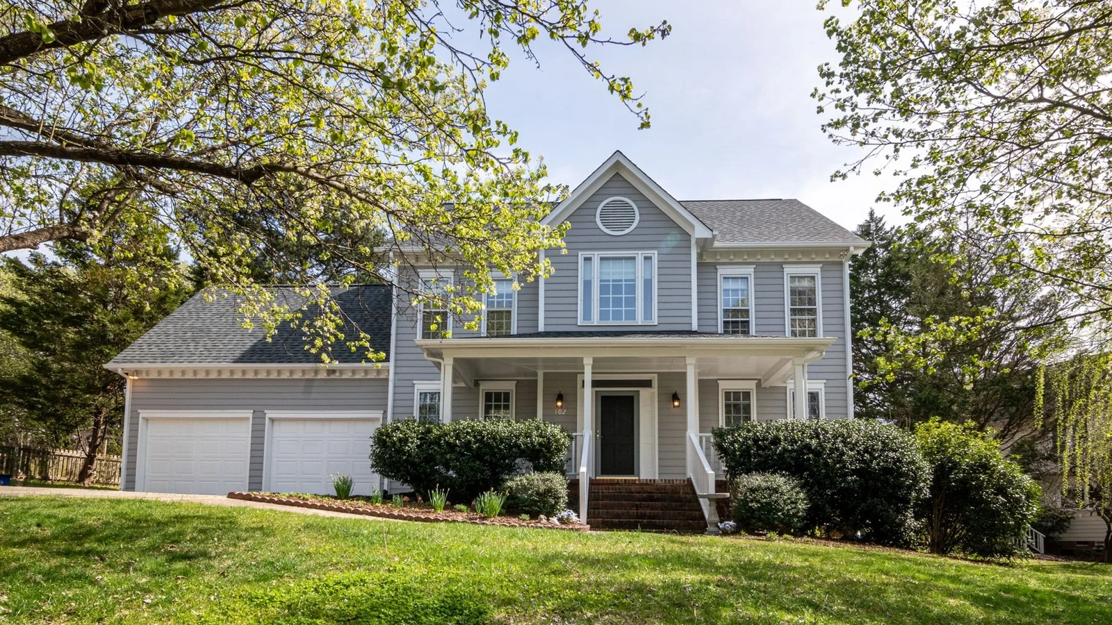 Two-story gray house with horizontal siding, white trim, porch and attached garage.