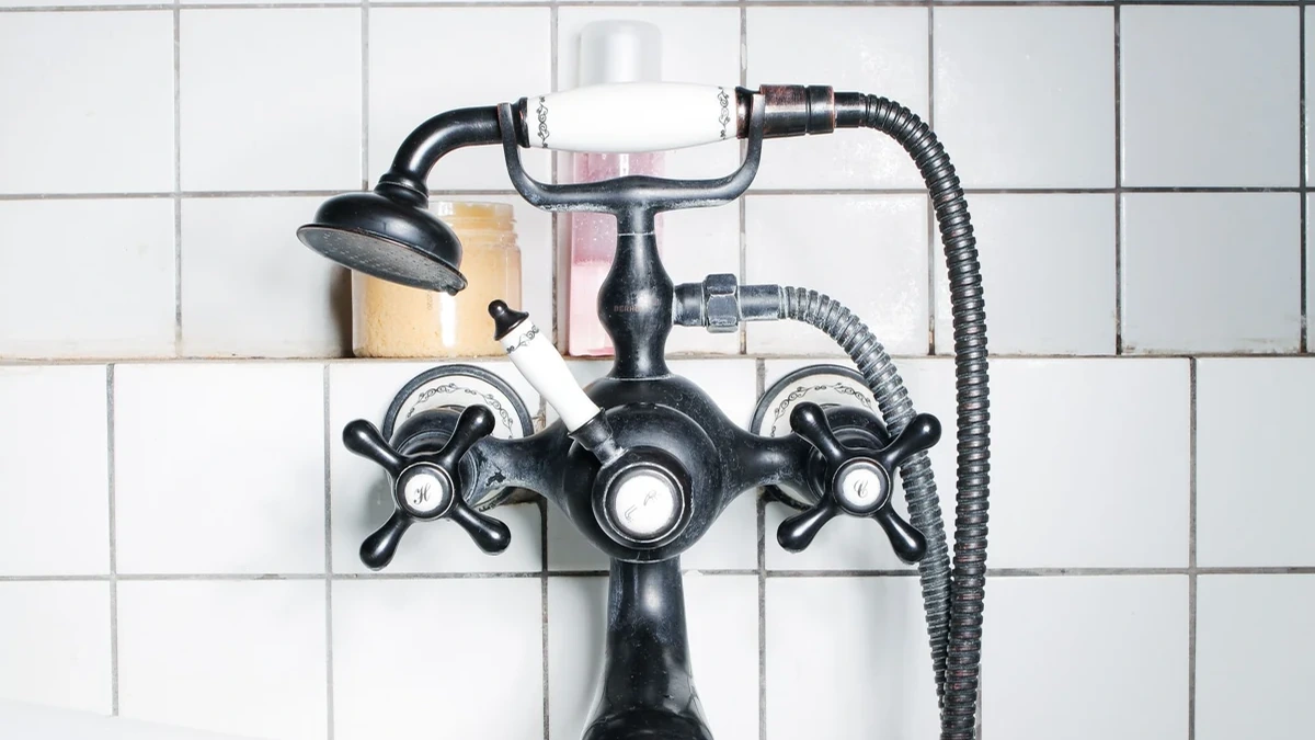 White square wall tiles and contrasting dark grout behind a traditional bath faucet.